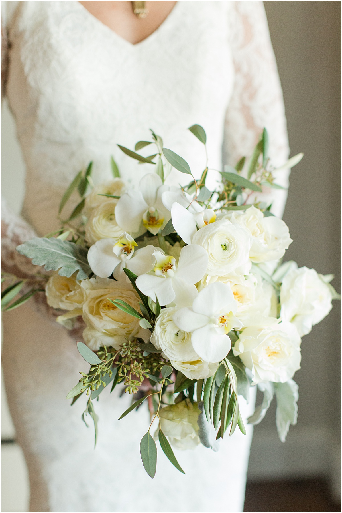 White bridal bouquet with orchids, roses, ranunculus, dusty miller and eucalyptus. 