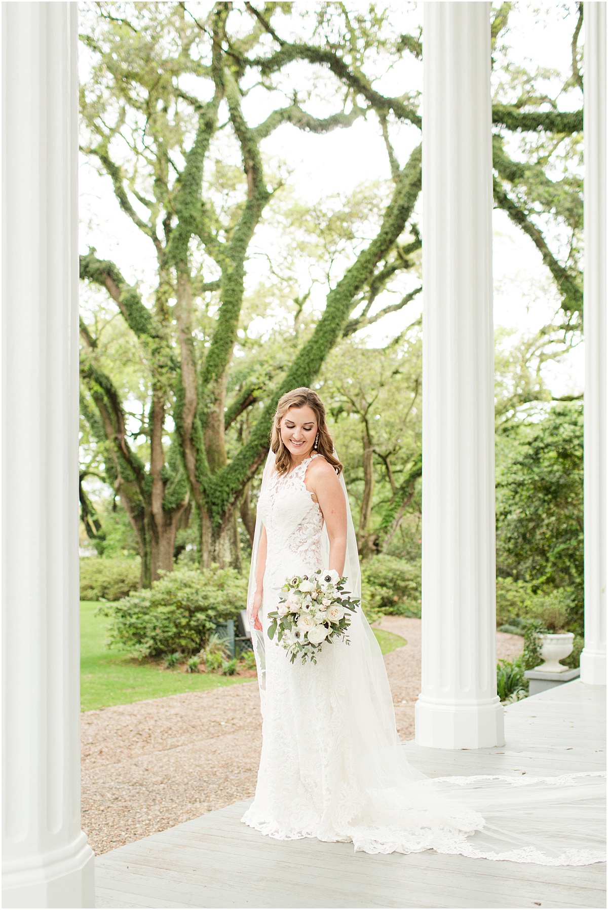 Bride wearing a lace gown and cathedral length veil standing on the porch at the Bragg-Mitchell Mansion in Mobile Alabama