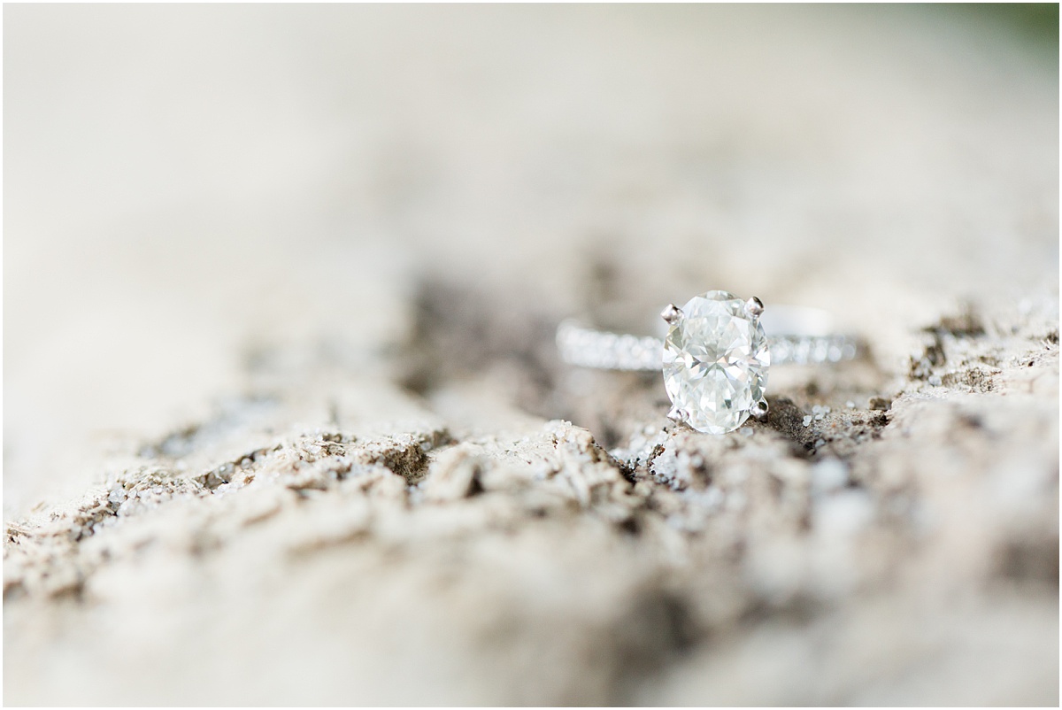 Close up photo of a diamond ring sitting on a piece of driftwood.