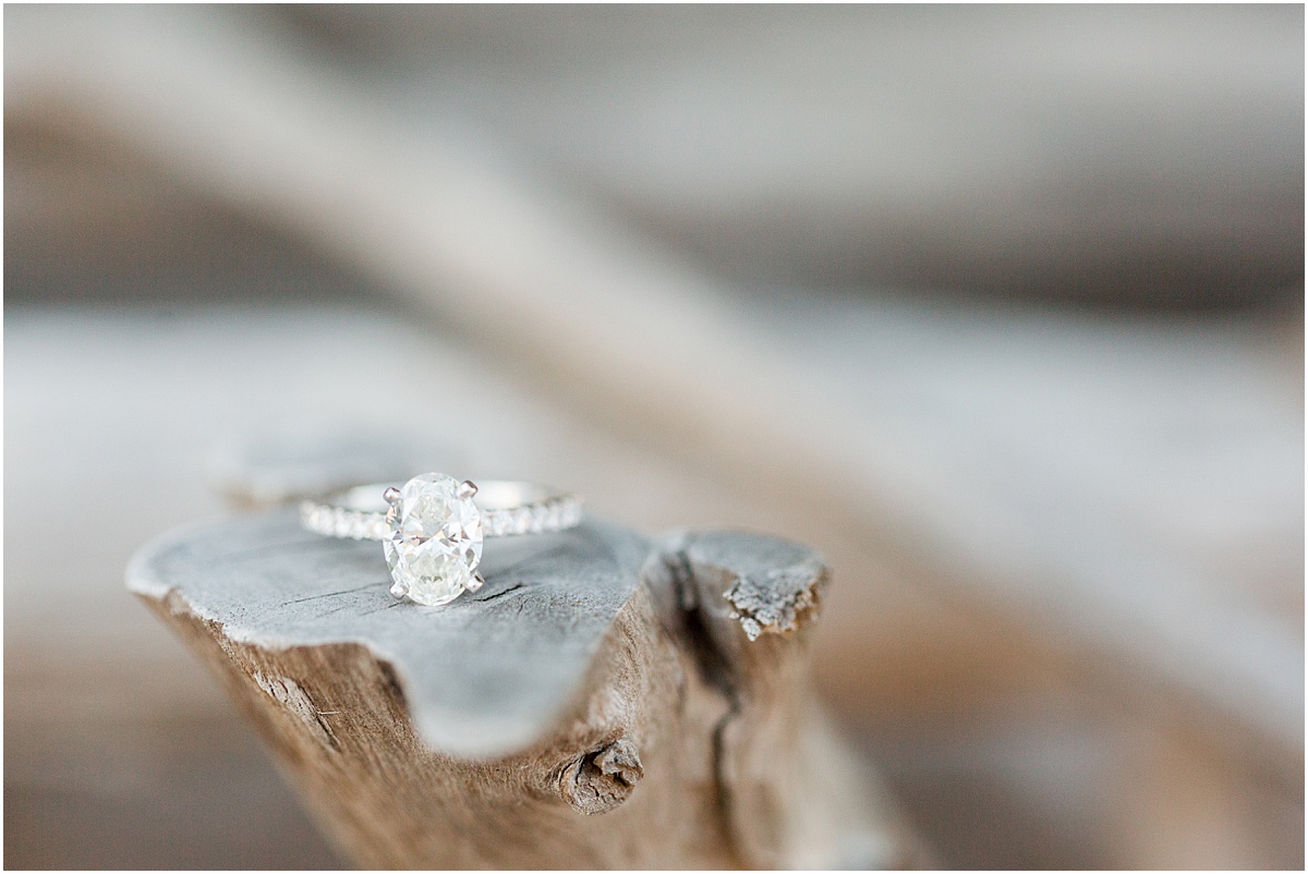 A diamond engagement ring sitting on a piece of carved wood