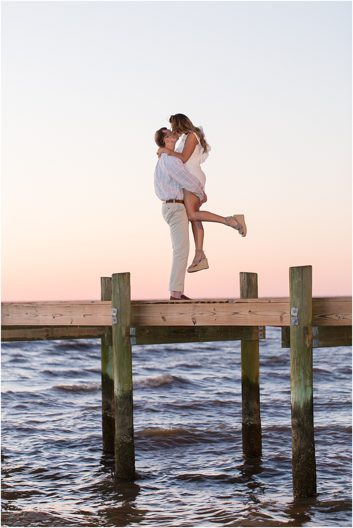 A man and woman kissing on Fairhope Pier at sunset in Fairhope Alabama.