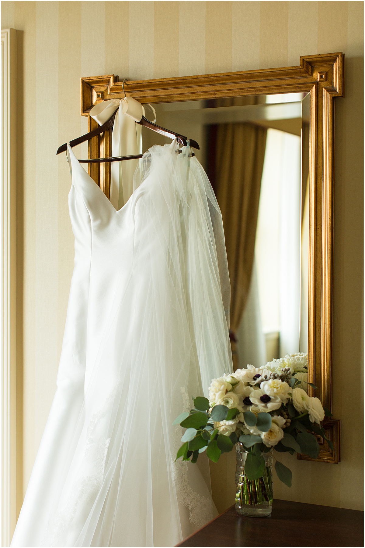 White wedding dress hanging on gold mirror at The Battle House Hotel