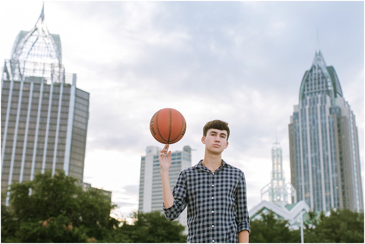 teenage boy with basketball with city skyline in background