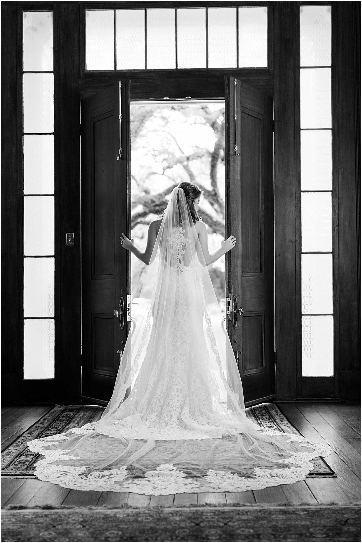A bride standing in front of the large wood doors at The Bragg-Mitchell Mansion looking out into the front lawn.