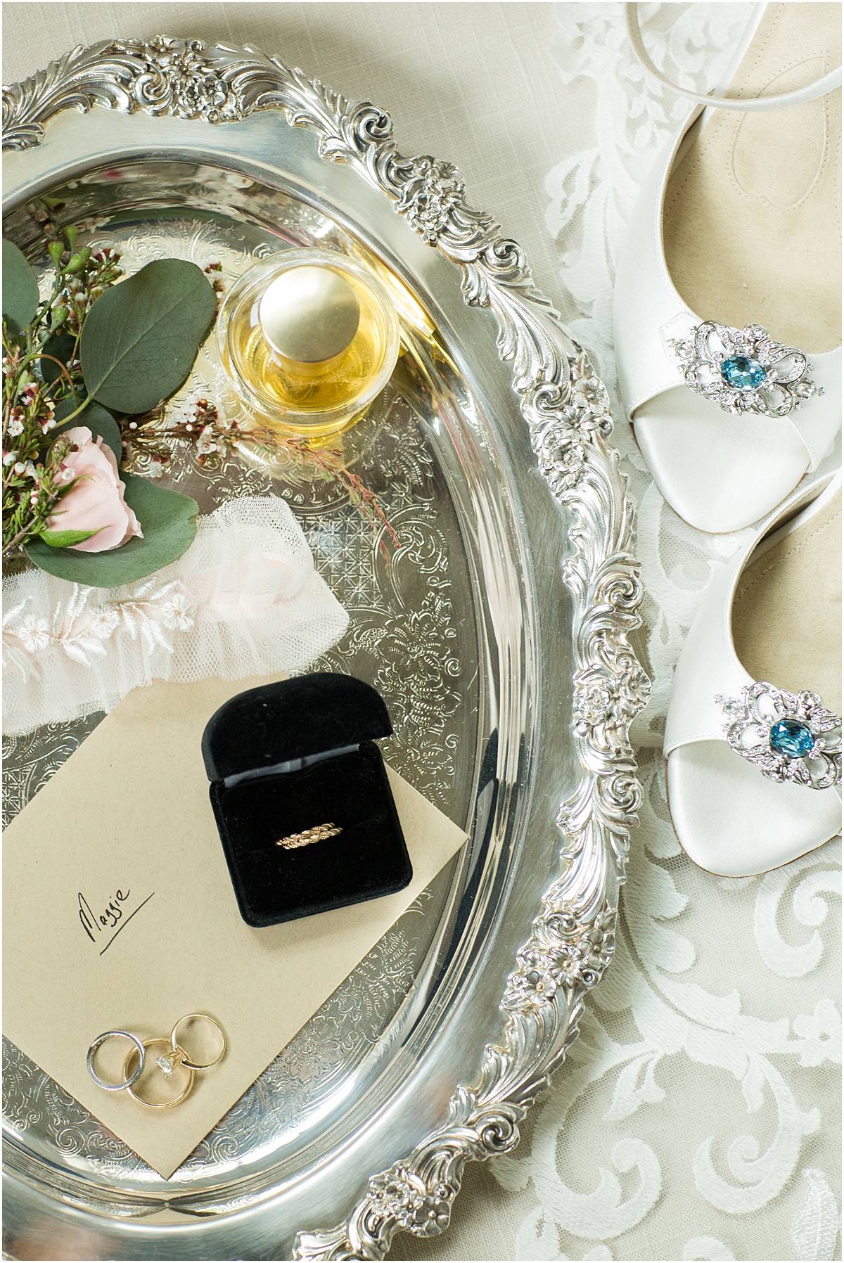 Vintage tray filled with a boutonniere, perfume bottle, ring box, rings and handwritten letter.