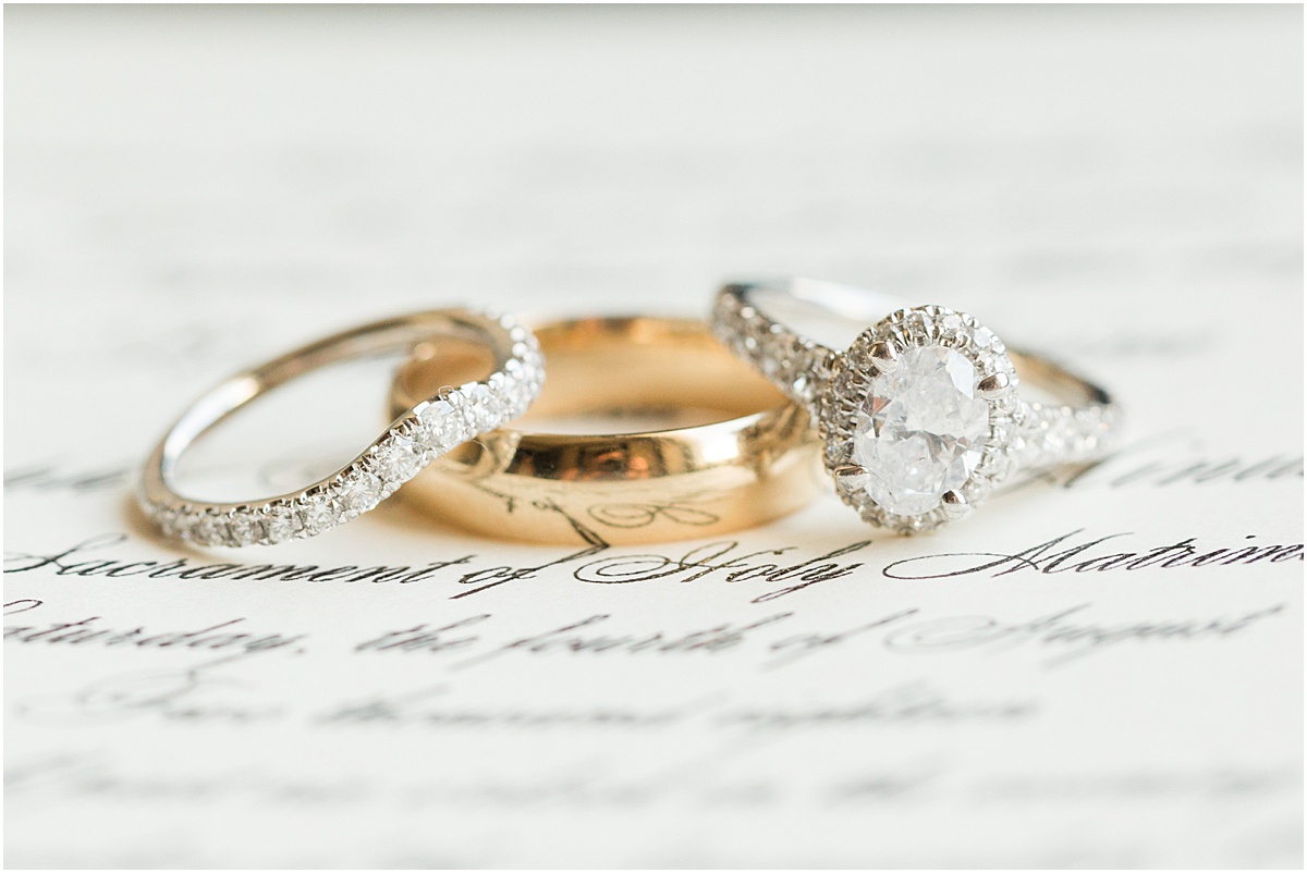 Two wedding bands and diamond engagement ring on wedding invitation.