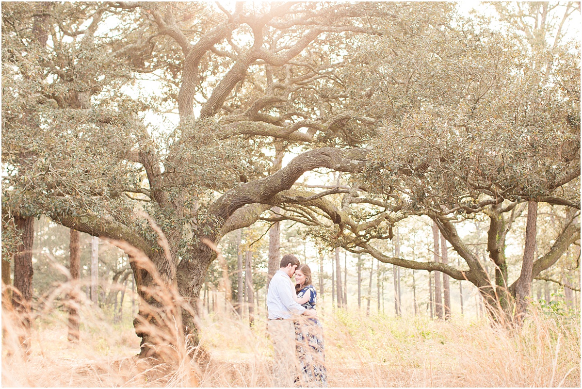 man and woman standing under giant oak tree in the longleaf pine forest